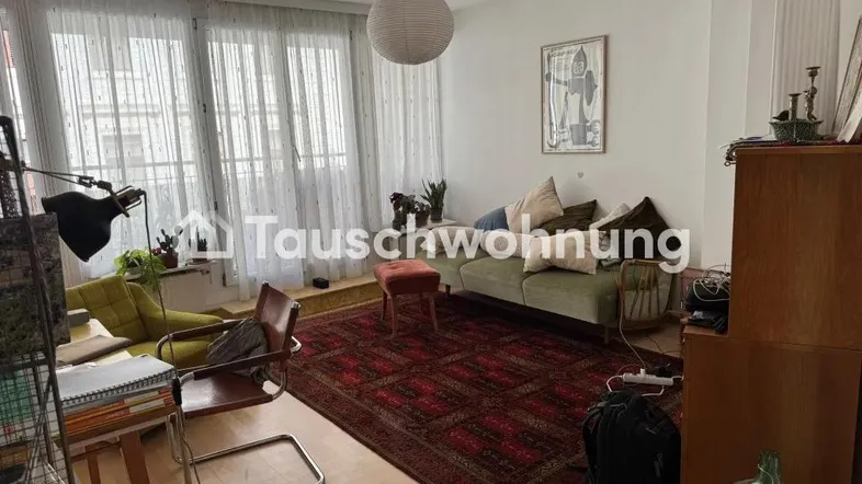 Helles Wohnzimmer mit großen Fenstern, einem Sofa und einem orientalischen Teppich.