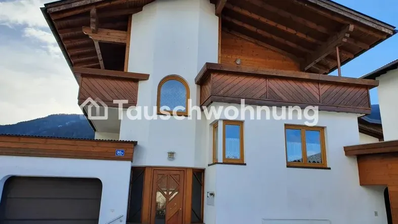 Traditionelles Haus mit weißer Fassade, Holzbalkonen und Satteldach.