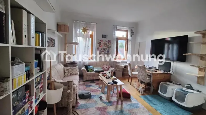 Helles Wohnzimmer mit Holzboden, Sofa, Schreibtisch und Bücherregal, gemütlich eingerichtet.