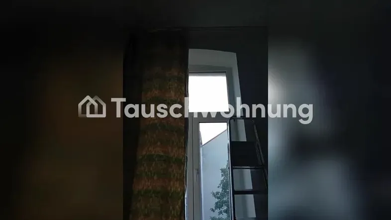 Dunkler Innenraum mit Fenster, Vorhang und einer Leiter, die auf eine Renovierung hindeutet.