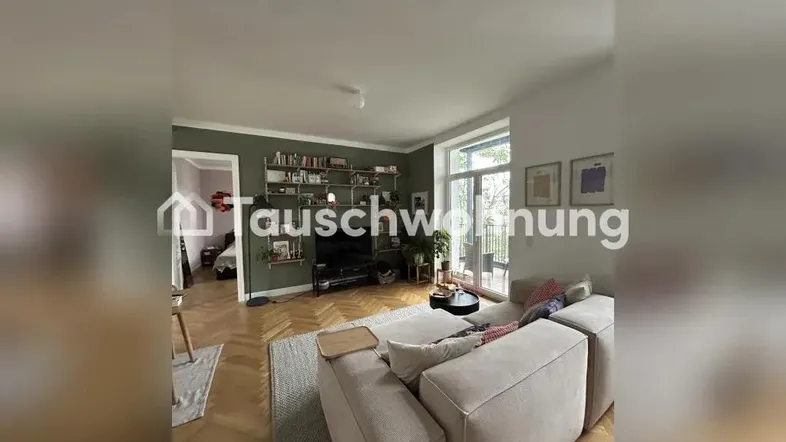 Helles Wohnzimmer mit beigem Sofa, Holzboden und Zugang zu einem Außenbereich.