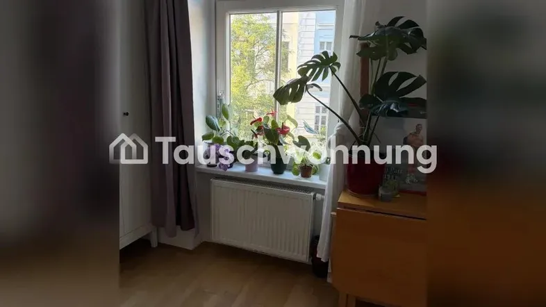 Helles Zimmer mit großem Fenster, Pflanzen auf der Fensterbank und Holzfußboden.