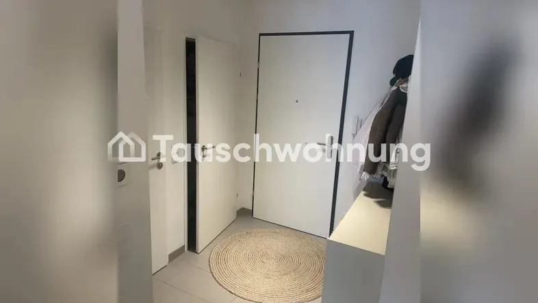 Heller Eingangsbereich mit Fliesenboden, Garderobe und moderner Einrichtung.