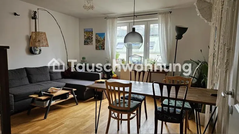 Gemütlicher Wohn-Essbereich mit Sofa, Esstisch und Blick aus dem Fenster.