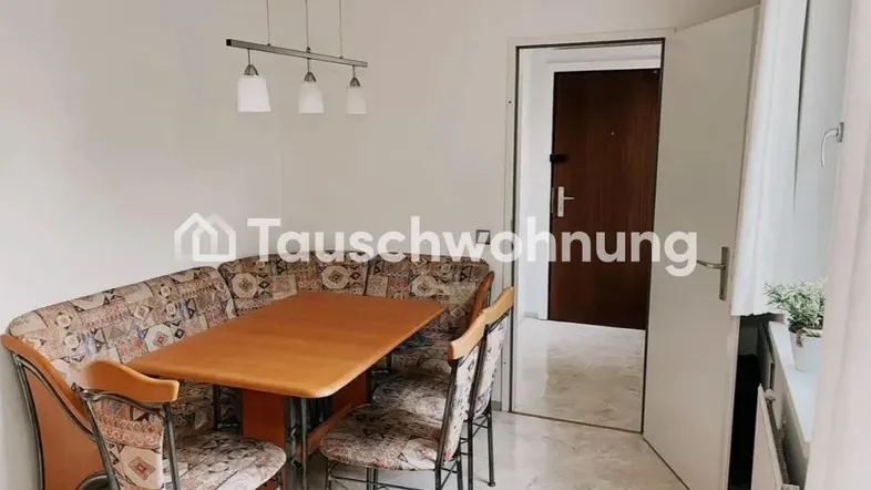 Gemütlicher Essbereich mit Eckbank, Holztisch und hellem Fliesenboden, der in den Eingangsbereich führt.
