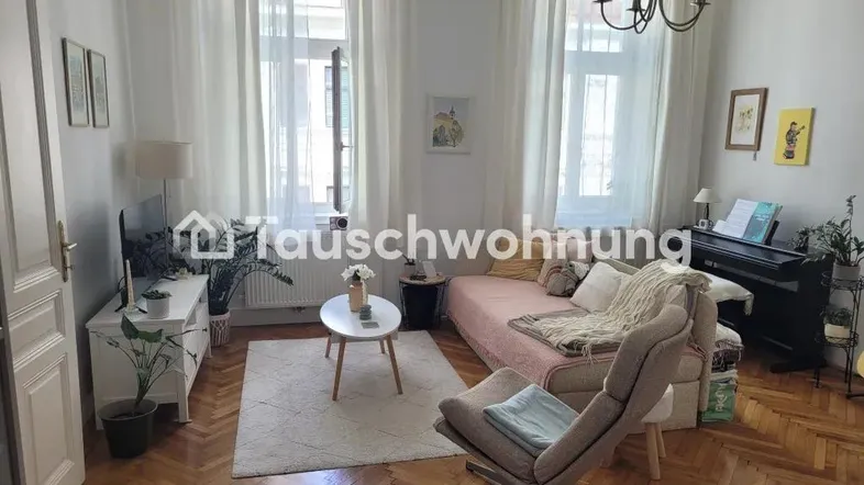 Helles Wohnzimmer mit Fischgrätparkett, großen Fenstern und gemütlicher Einrichtung.
