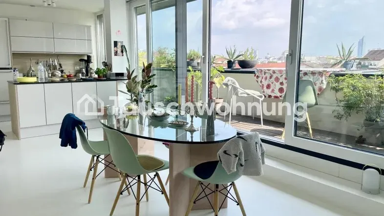 Heller offener Wohn-Essbereich mit moderner Küche, Esstisch und Zugang zu einer großen Terrasse.
