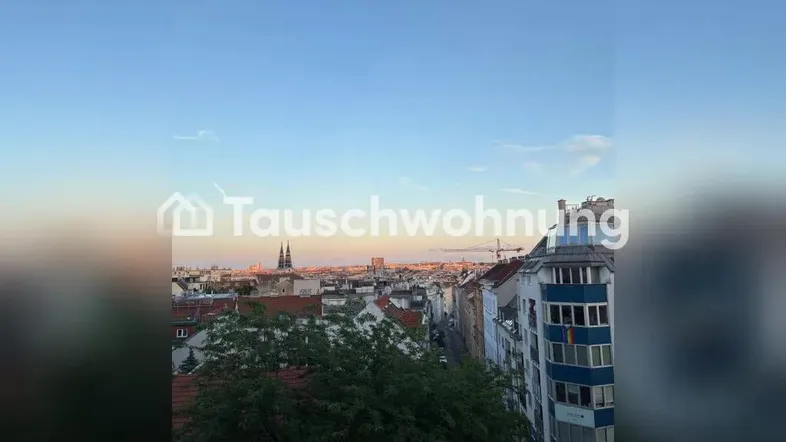 Weitläufiger Blick über die Dächer der Stadt mit historischer Kirche im Hintergrund bei Sonnenuntergang.