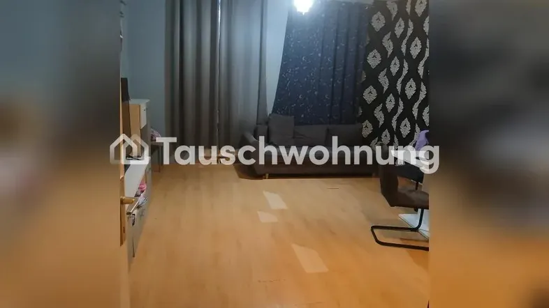 Geräumiges Wohnzimmer mit hellem Laminatboden, dunklen Vorhängen und einem Sofa.