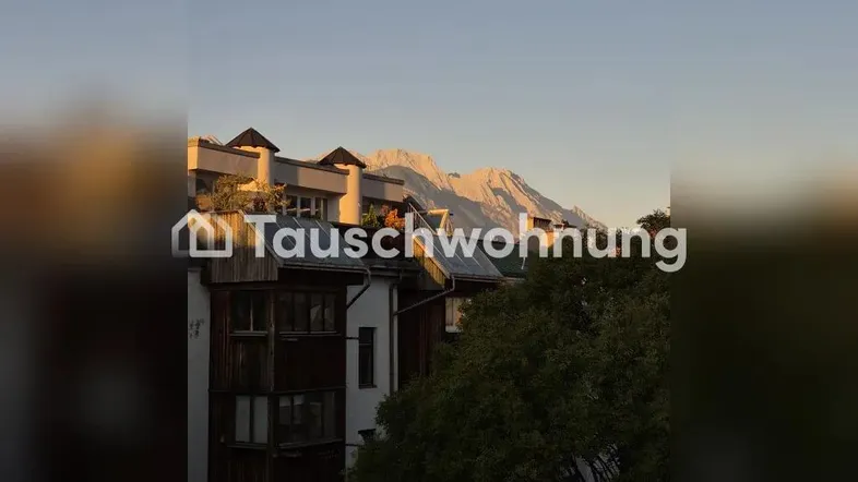 Gebäude mit Bergblick bei Sonnenuntergang, umgeben von Bäumen und mit Balkonen.