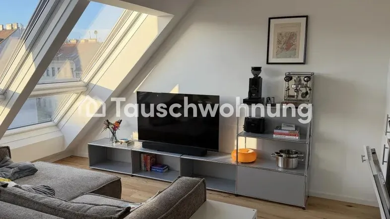 Helles Wohnzimmer im Dachgeschoss mit großen Dachfenstern, Holzboden und moderner Einrichtung.