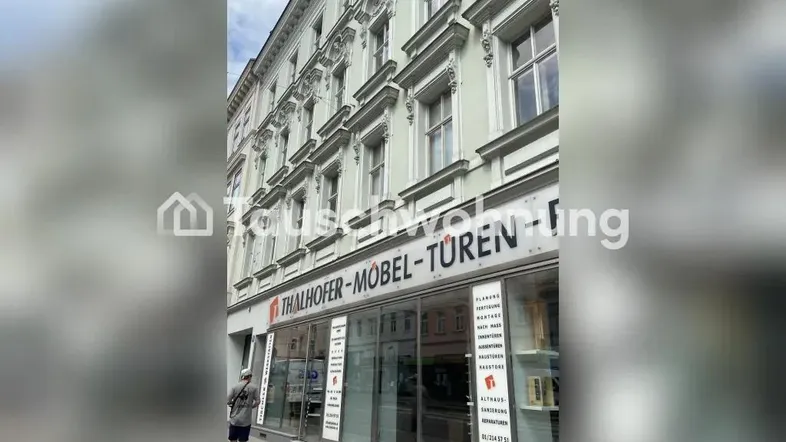 Historische Fassade eines Gebäudes mit Geschäftsräumen im Erdgeschoss und klassischen Fenstern.