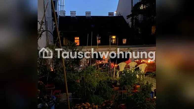 Abendliche Gartenszene mit Pflanzen, Sitzgelegenheiten und stimmungsvoller Beleuchtung im Hinterhof.