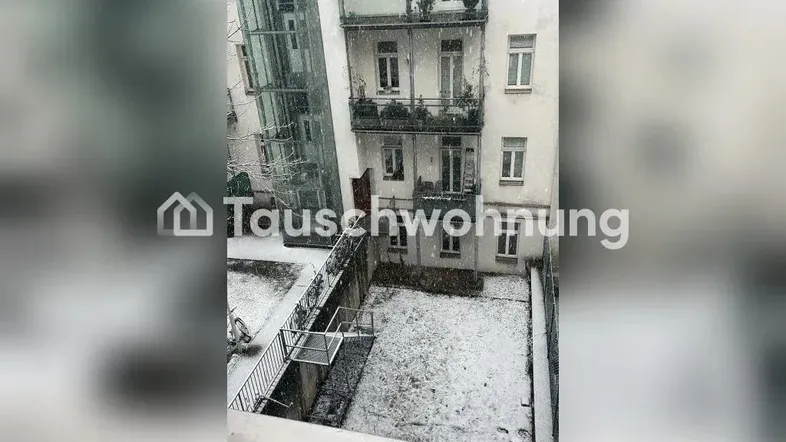 Blick aus dem Fenster auf einen verschneiten Innenhof mit angrenzendem Gebäude und externem Glasaufzug.