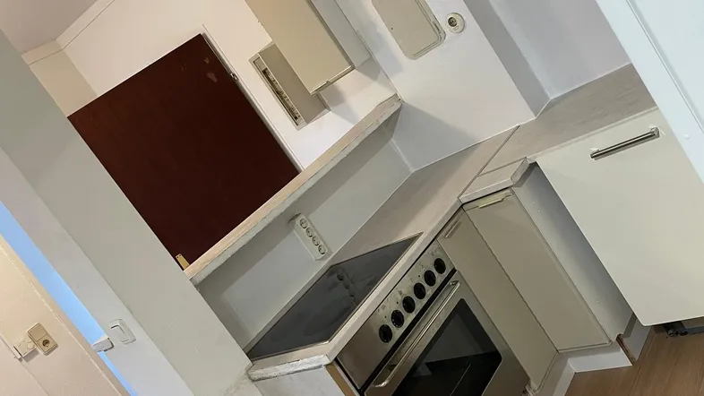 Kleine Küche mit Einbauherd, hellen Schränken und Laminatboden, funktional und kompakt.