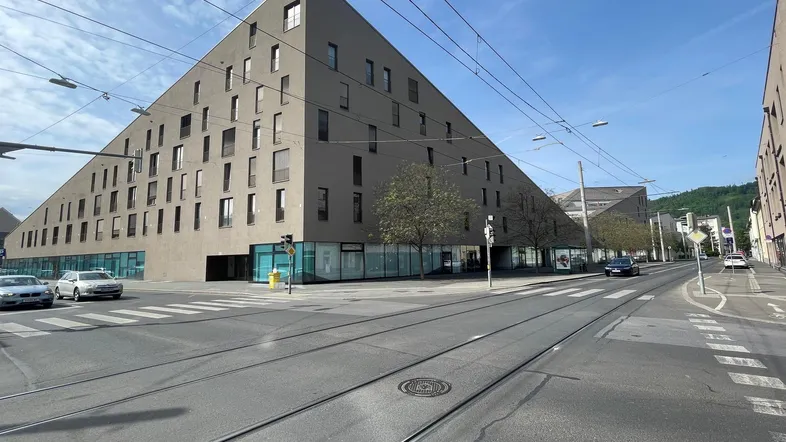 Modernes Gebäude mit ungewöhnlicher, dreieckiger Architektur und vielen Fenstern an einer Stadtstraße.