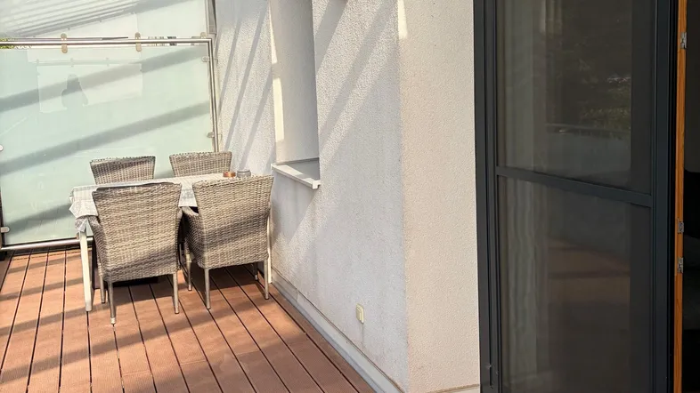 Überdachte Terrasse mit Holzboden und Sitzgelegenheiten, ideal für entspannte Stunden im Freien.