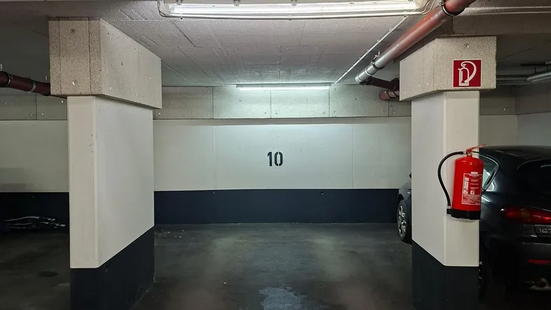 Tiefgaragenstellplatz Nummer 10 mit Betonpfeilern und Brandschutzvorrichtung.