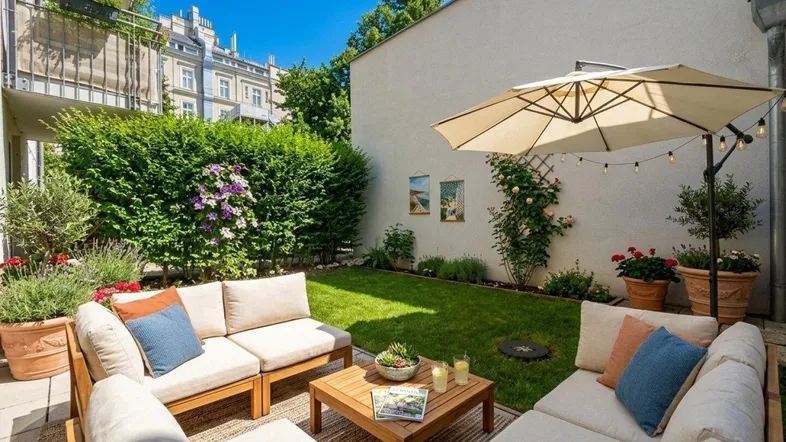 Gemütlicher Gartenbereich mit Sitzgelegenheiten, Sonnenschirm und gepflegter Hecke.