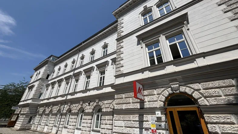 Historisches Gebäude mit klassischer Architektur und steinernen Fassadendetails unter blauem Himmel.
