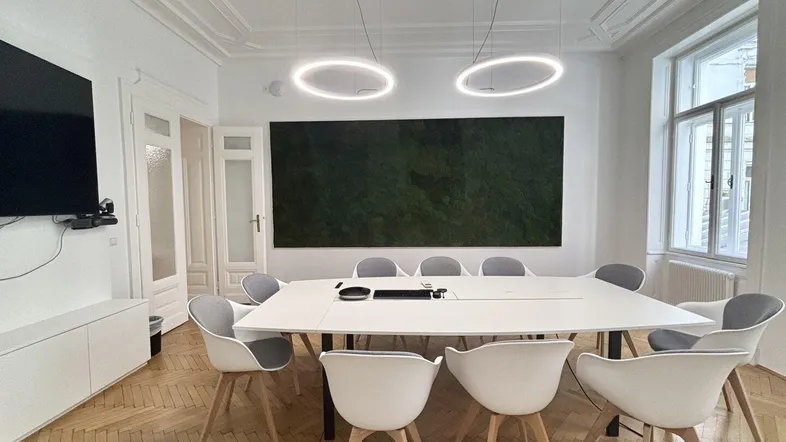 Moderner Konferenzraum mit Fischgrätparkett, großer Tafel, ergonomischen Stühlen und einer Mooswand.