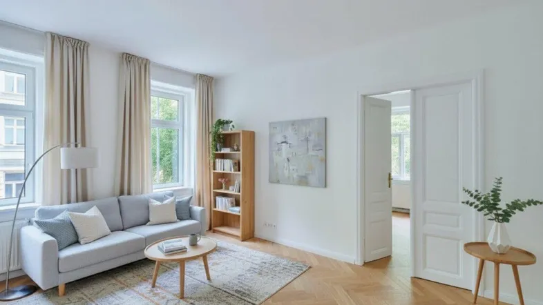 Helles Wohnzimmer mit Fischgrätparkett, modernem Sofa und Blick ins Grüne durch große Fenster.