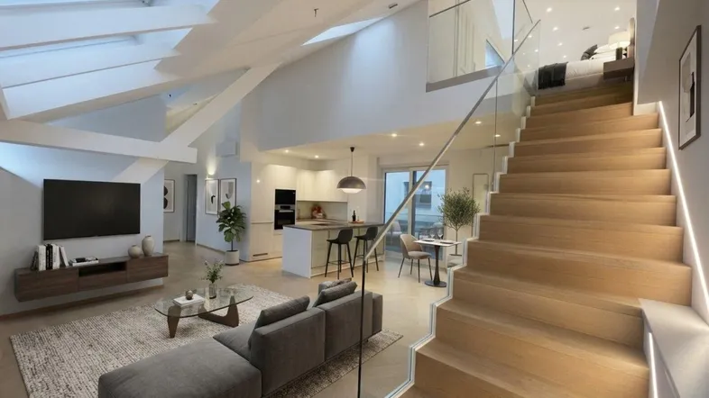 Großzügiger offener Wohn- und Essbereich mit moderner Küche, hohen Decken und eleganter Holztreppe.