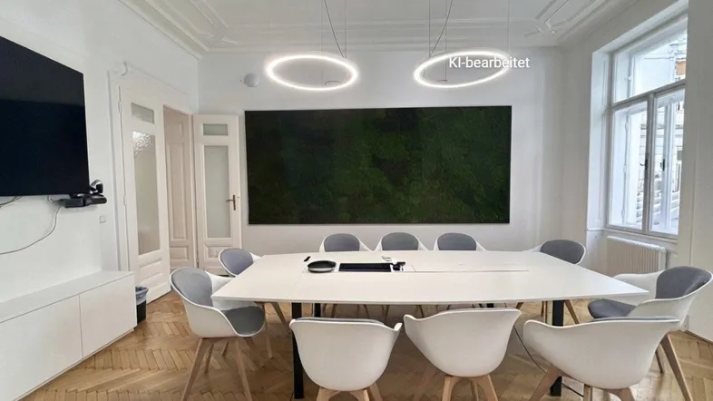 Moderner Konferenzraum mit großem Tisch, bequemen Stühlen und einer grünen Mooswand als Akzent.