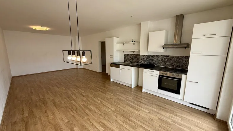 Moderne Einbauküche mit weißen Schränken, dunkler Arbeitsplatte und integrierten Geräten.