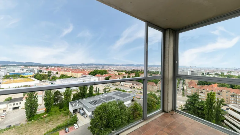 Geräumiger Balkon mit Fliesenboden und weitem Blick über die Stadt und die umliegende Landschaft.