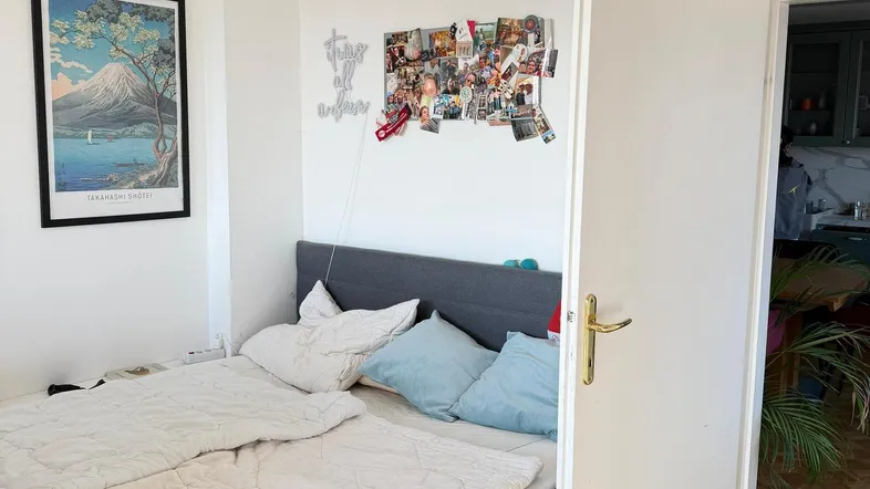 Gemütliches Schlafzimmer mit Doppelbett, Parkettboden und Zugang zu einem weiteren Raum.