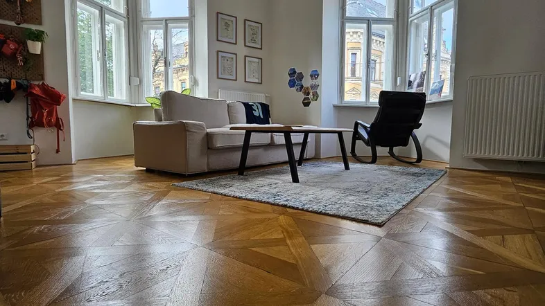 Helles Wohnzimmer mit Fischgrätparkett, Erkerfenstern und moderner Einrichtung.