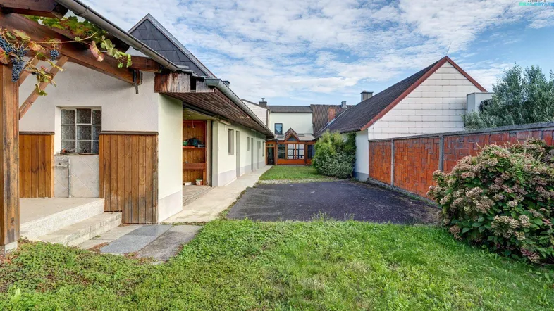 Ländliches Anwesen mit Nebengebäuden, gepflegtem Rasen und einem befestigten Weg.