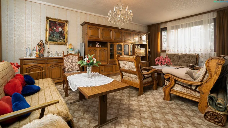 Gemütliches Wohnzimmer im traditionellen Stil mit Teppichboden und einem eleganten Kronleuchter.