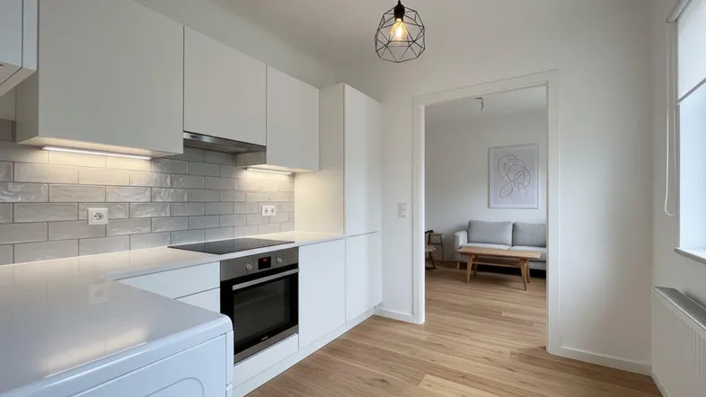 Moderne weiße Küche mit integrierten Geräten, hellen Fliesen und Holzboden, offen zum Wohnbereich.
