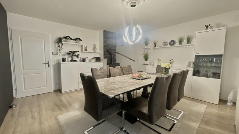 Eleganter Essbereich mit großem Esstisch, modernen Stühlen und hellem Laminatboden für stilvolle Mahlzeiten.