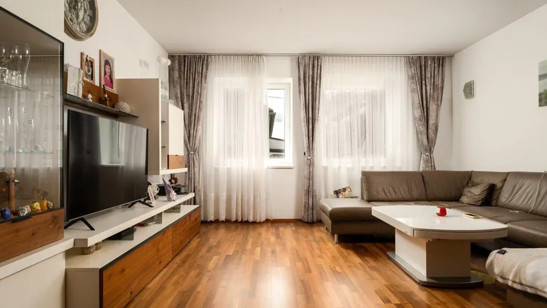 Geräumiges Wohnzimmer mit Holzboden, großem Sofa und TV-Möbeln, perfekt zum Entspannen.