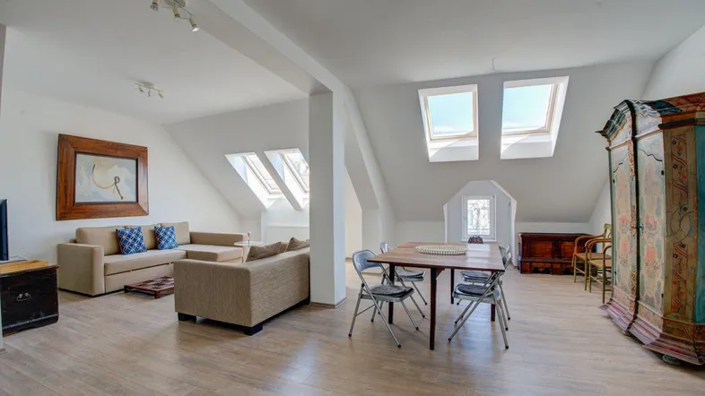 Helles Wohn- und Esszimmer im Dachgeschoss mit Holzboden und mehreren Dachfenstern.