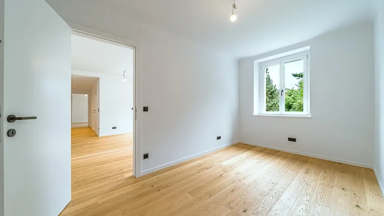 Geräumiges, helles Schlafzimmer mit Holzboden und Zugang zum Flur.