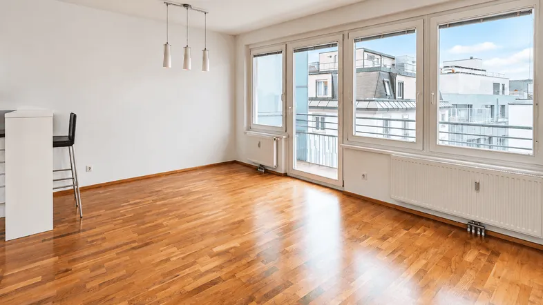 Helles Wohnzimmer mit Parkettboden, großen Fenstern und Blick auf die Stadt.