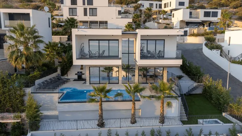 Moderne Villa mit Pool, Palmen und Meerblick in einer Wohnsiedlung.