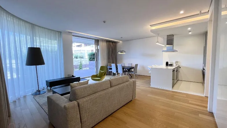 Geräumiger offener Wohn- und Essbereich mit moderner Küche, Holzboden und Zugang zur Terrasse.