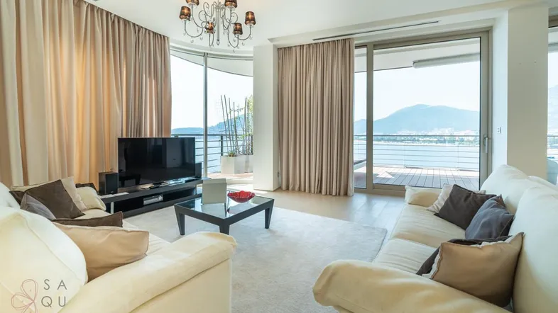 Helles Wohnzimmer mit großen Fenstern, Meerblick und modernem Kronleuchter.