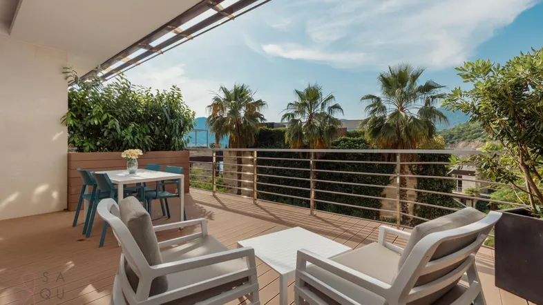 Geräumige Terrasse mit modernen Gartenmöbeln, Essbereich und Blick auf das Meer und Palmen.