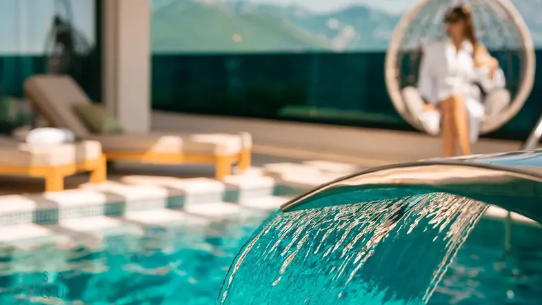 Luxuriöser Poolbereich mit Wasserfall, Liegestühlen und atemberaubendem Bergblick.