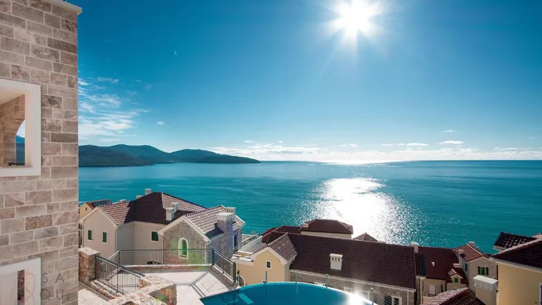Sonniger Außenbereich mit Pool und atemberaubendem Blick auf das Meer und die umliegenden Berge.