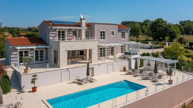 Elegante Villa mit großem Pool, Sonnenterrasse und Blick auf die grüne Landschaft.