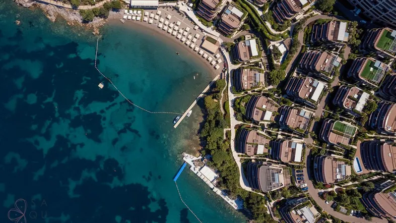 Luftaufnahme eines luxuriösen Küstenresorts mit privaten Stränden und modernen Gebäuden am Meer.