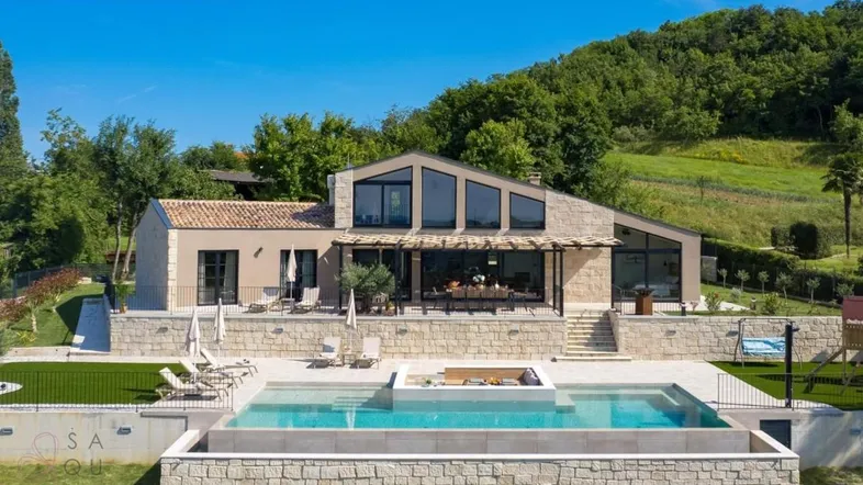 Moderne Villa mit großem Pool, Sonnenterrasse und weitem Blick auf die grüne Landschaft.