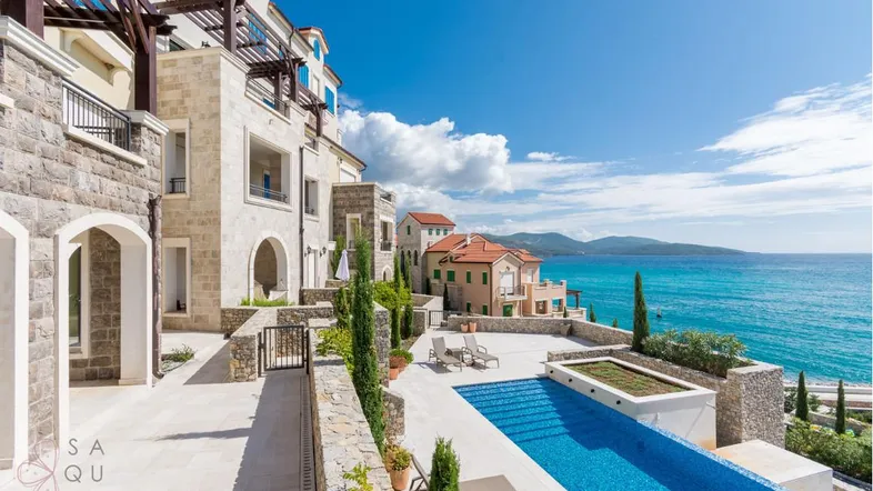 Luxuriöse Wohnanlage mit Infinity-Pool und atemberaubendem Meerblick unter blauem Himmel.